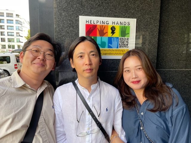 Internationaler-Austausch-bei-helpinghands: Drei asiatische Menschen lächeln in die Kamera