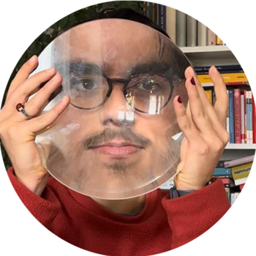 Wotziges Portrait von Miad Masouri, der sich eine große Lupe vor sein Gesicht hält.